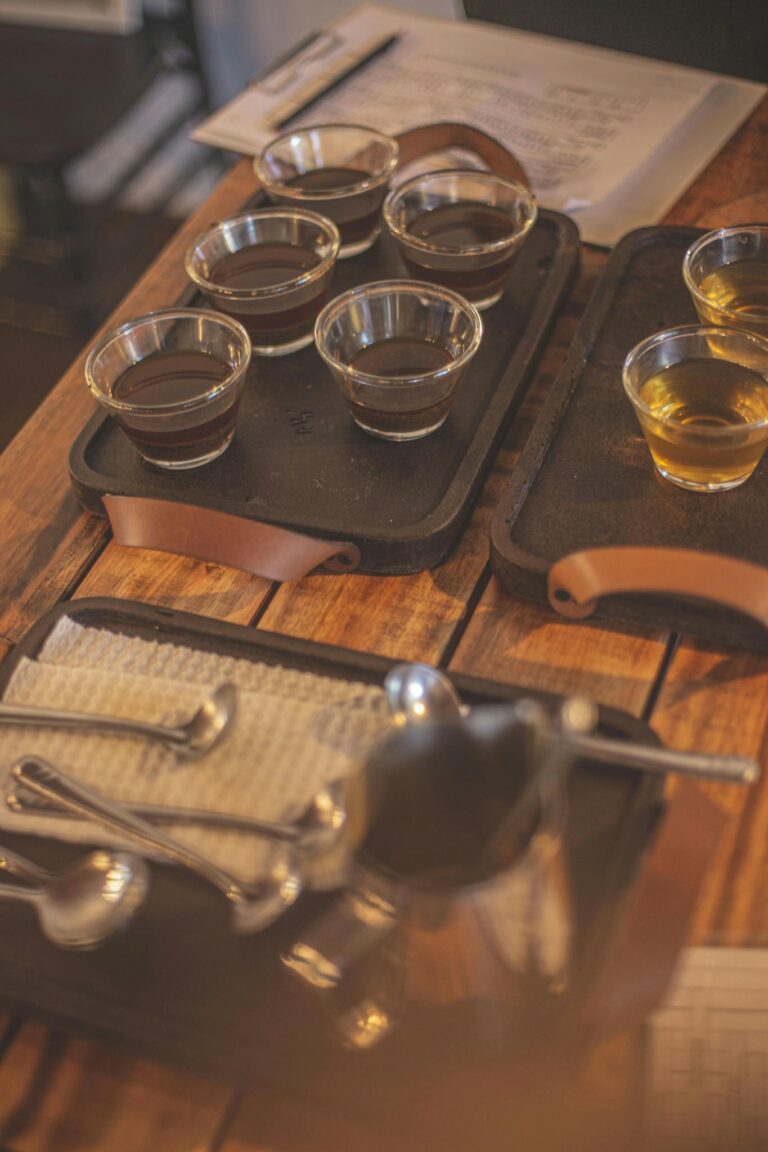 An inviting coffee tasting setup featuring cups of coffee on a rustic wooden table with spoons and trays.