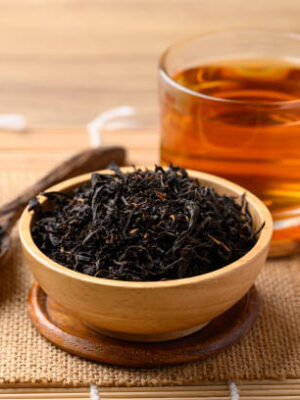 Dried black tea leaves and hot tea drink in cup glass